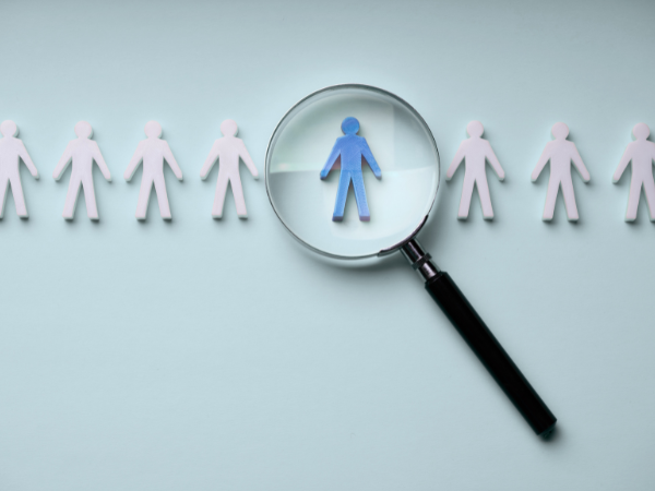 Lupe fokussiert eine Person in einer Gruppe als Symbol für selektive Wahrnehmung und verzerrte Beurteilung